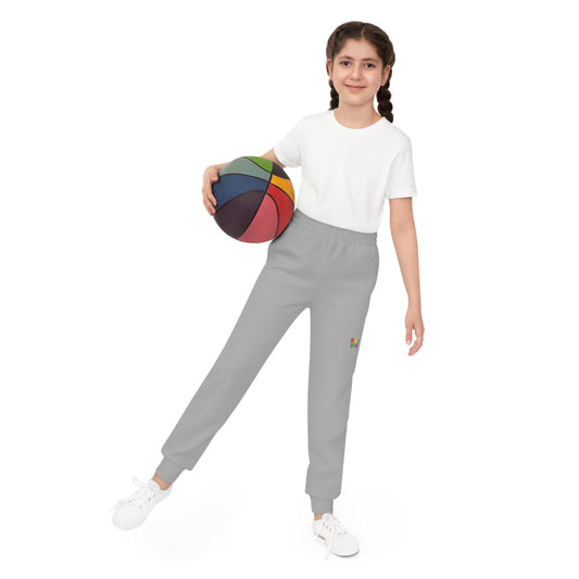 Barn iført grå KUL KID joggebukse, stående med basketball i hånden.