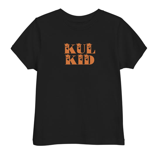 Barn iført svart T-skjorte med oransje KUL KID-trykk, stående på lys bakgrunn.